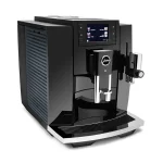 A sleek JURA E8 espresso machine black, displaying its full-color screen and coffee spout
